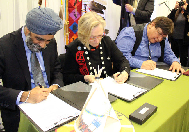 Minister of National Defence Harjit Sajjan (left), Minister of Indigenous and Northern Affairs Dr. Carolyn Bennett and Kettle and Stony Point Chief Tom Bressette sign the final Ipperwash settlement